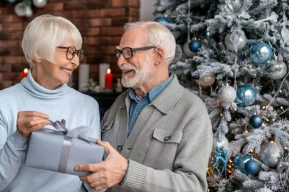Senior man giving a christmas gift to his wife at home