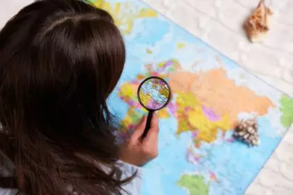The girl explores the world map with a magnifying glass